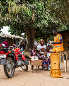 Man with woman and chid in African village and motorcycle