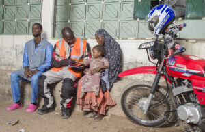 Motorcycle rider with family and bike in African village